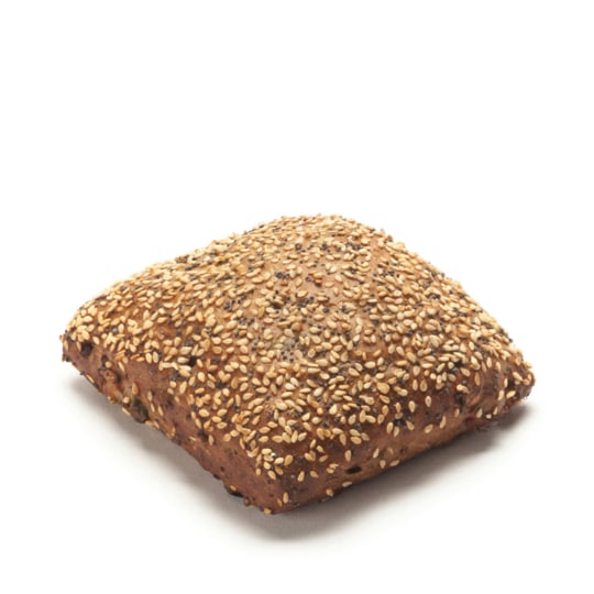 Ein quadratisches, braunes Mehrkornbrötchen, belegt mit einer großzügigen Menge an verschiedenen Samen, einschließlich Sesam, auf weißem Hintergrund.
