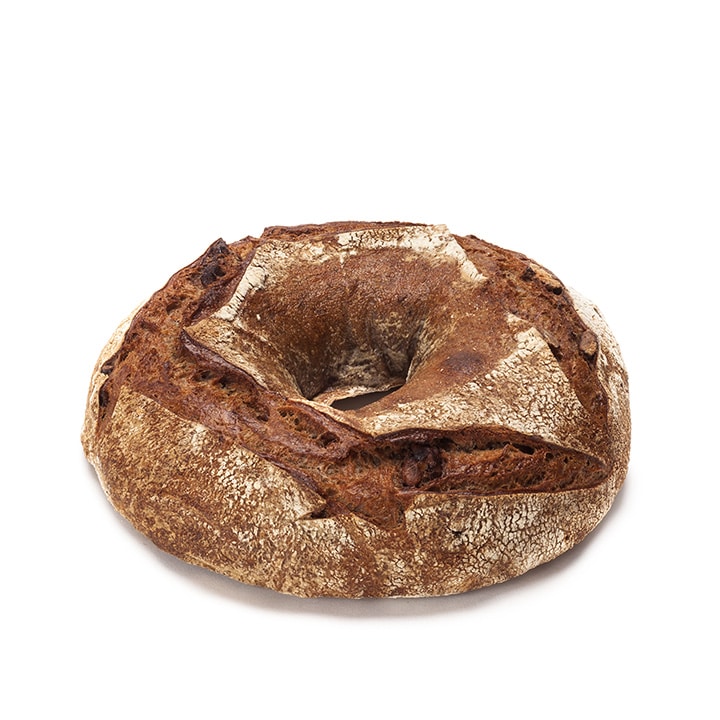 Ein runder, rustikaler Brotlaib mit einer dicken, knusprigen Außenseite und einem Loch in der Mitte, das an einen großen Bagel oder Ring erinnert, auf einem schlichten weißen Hintergrund.