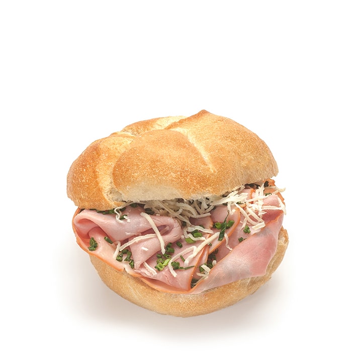 Ein rundes Sandwichbrötchen, gefüllt mit Schinkenscheiben, geriebenem Käse und gehacktem Schnittlauch, auf weißem Hintergrund.