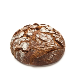 Ein runder Laib rustikalen, dunkelbraunen Brotes mit einer knusprigen Oberfläche und weißem Mehl auf weißem Hintergrund.
