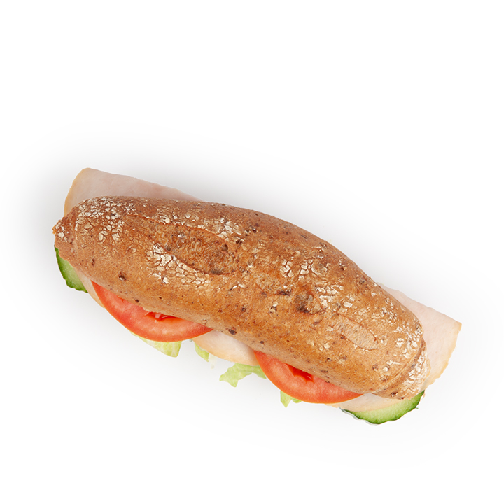 Ein Sandwich mit einem Vollkornbaguette, gefüllt mit Putenscheiben, Tomaten, Salat und Gurken, fotografiert auf einem weißen Hintergrund.