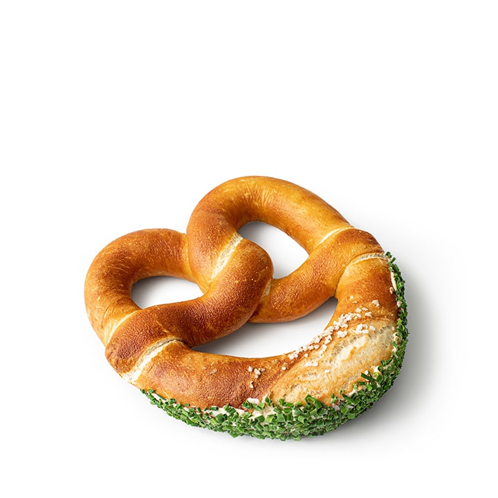 Eine weiche Brezel, bestreut mit grobem Salz und garniert mit gehacktem Schnittlauch an einem Rand, vor weißem Hintergrund.
