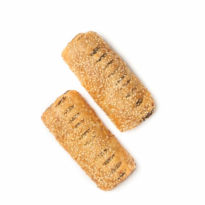 Zwei rechteckige, mit Sesam bestreute Blätterteigtaschen auf weißem Hintergrund. Jedes Gebäck hat oben kleine Schlitze, die eine dunkle Füllung im Inneren offenbaren.