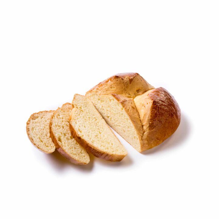 Ein geflochtener Brotlaib, teilweise aufgeschnitten, mit drei Scheiben, die vor dem verbleibenden Laib auf einem weißen Hintergrund liegen.