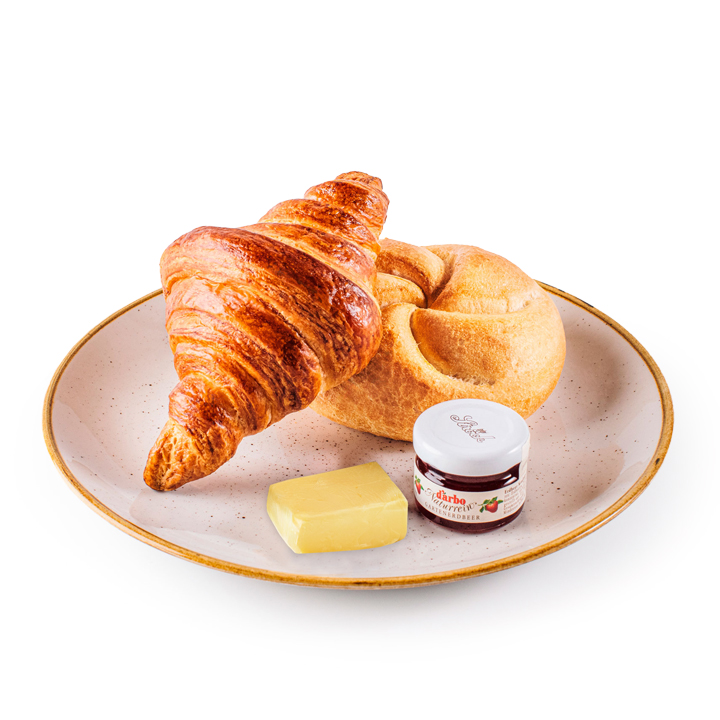 Ein Teller mit einem Croissant, einem runden Brötchen, einem Stück Butter und einem kleinen Glas Erdbeermarmelade, alles auf einem hellen, gesprenkelten Teller vor weißem Hintergrund angeordnet.