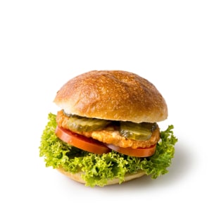 Ein gebratenes Hühnchensandwich mit Blattsalat, Tomatenscheiben, Gurkenchips und einem goldenen Brötchen, dargestellt vor einem schlichten weißen Hintergrund.