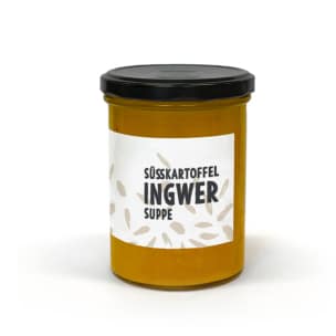 Ein Glasgefäß mit schwarzem Deckel, das eine Orangensuppe enthält. Auf dem Etikett steht "Süßkartoffel Ingwer Suppe", was darauf hinweist, dass es sich um Süßkartoffel-Ingwer-Suppe handelt. Das Etikett ist weiß mit dekorativen beigen Blattmustern.