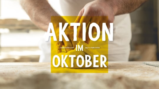 Nahaufnahme der Hände einer Person, die einen Teig auf einer bemehlten Fläche formt. Der überlagerte Text in Deutsch lautet: "AKTION IM OKTOBER" in fetten weißen Buchstaben auf einem gelben Quadrat.