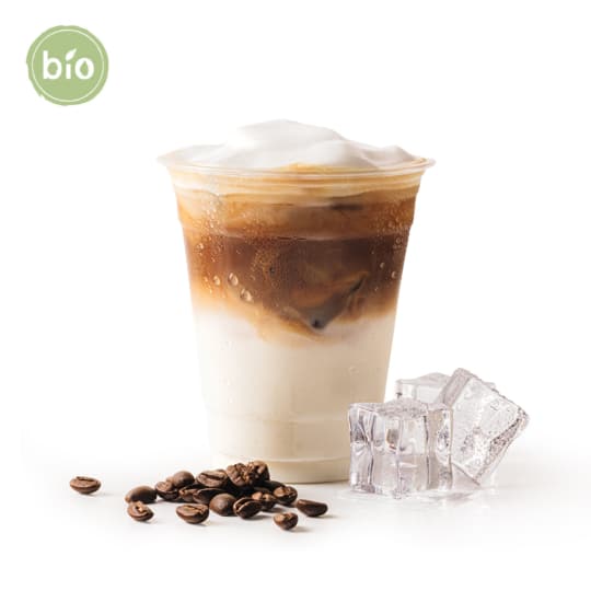 Ein Plastikbecher mit Eiskaffee, Milch und Schaum, neben Kaffeebohnen und Eiswürfeln, auf weißem Hintergrund. Ein grünes "Bio"-Etikett erscheint in der oberen linken Ecke.