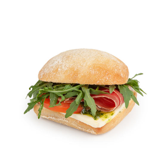Ein Ciabatta-Sandwich, gefüllt mit Rucola, Tomatenscheiben, Pökelfleisch, Weißkäse und grüner Pestosauce, isoliert auf weißem Hintergrund.