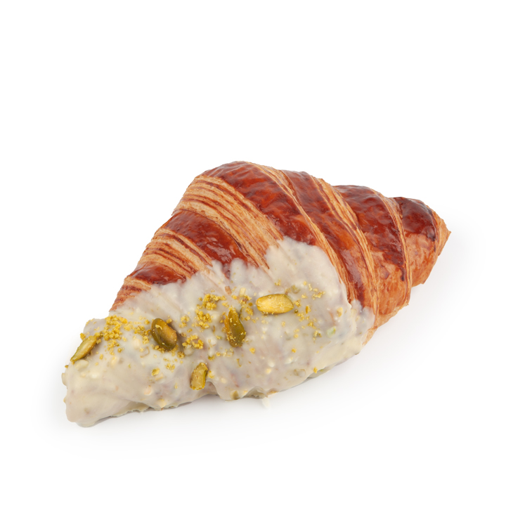 Ein goldbraunes Croissant, das teilweise in weißen Zuckerguss getaucht ist, mit zerstoßenen Pistazien und einigen ganzen Pistazienstücken bestreut, vor einem weißen Hintergrund.