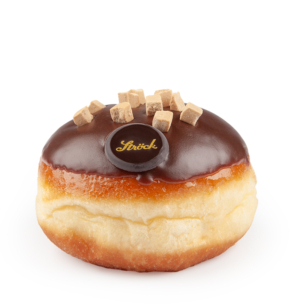 Ein runder Krapfen mit einer glänzenden Schicht aus Schokoladenglasur, kleinen Karamellwürfeln und einem runden Schokoladenstück mit der Aufschrift "Sírick" auf weißem Hintergrund.