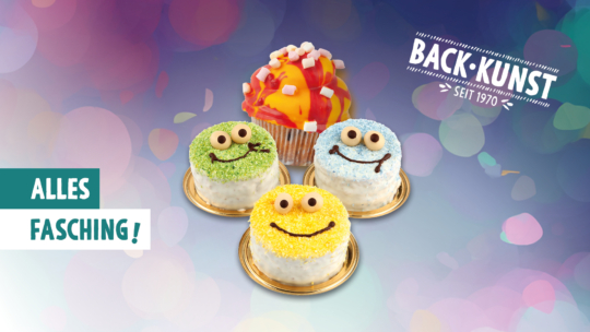 Drei bunte, lächelnde Mini-Kuchen mit Augen und Zuckerguss sind vor einem dekorierten orangefarbenen Cupcake angeordnet. Der Hintergrund ist unscharf und festlich. Der Text lautet "Back-Kunst seit 1970" und "Alles Fasching!".