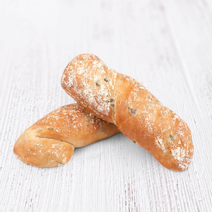 Zwei rustikale, mit Mehl bestäubte Brotstücke liegen auf einer weißen Holzfläche. Ein blauer Kreis in der oberen linken Ecke zeigt das Wort "vegan".