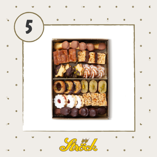 A box of assorted festive cookies and pastries, neatly arranged in rows, featuring chocolate-dipped treats, nut-covered bites, and sugar-dusted pastries. The background has a number 5 and a Ströck logo at the bottom.