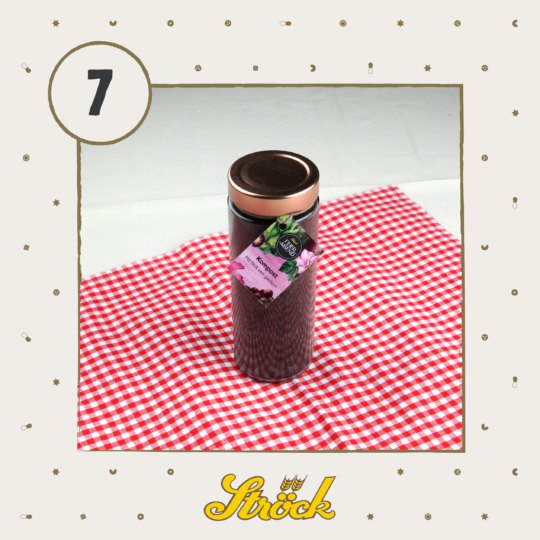 A jar of dark jam with a gold lid and a pink label sits on a red and white checkered cloth. The number 7 is in a circle at the top left, and Ströck is written in yellow at the bottom.
