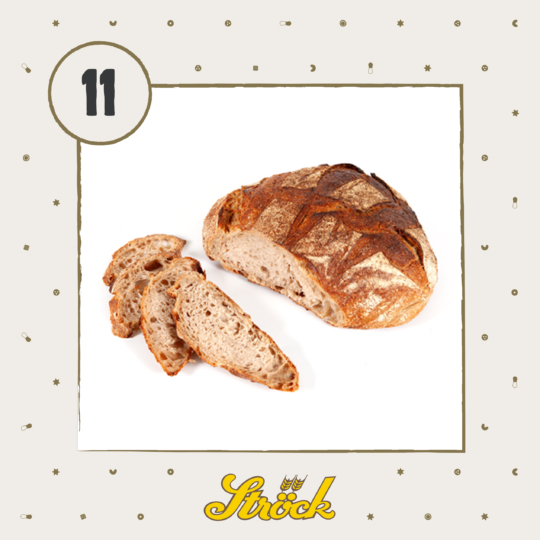 A round loaf of rustic bread with a brown crust sits on a white surface, next to three slices of the same bread. The number 11 and the Ströck logo appear on a patterned background.