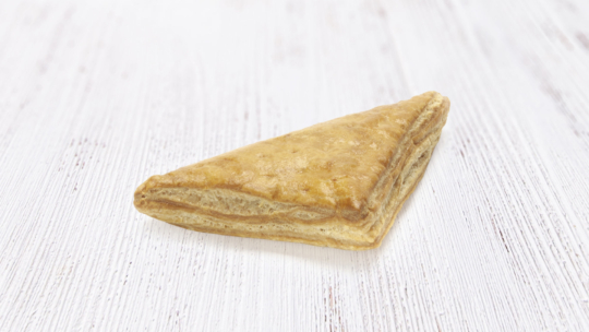 Auf einer hellen Holzunterlage liegt ein goldbrauner, flockiger, dreieckiger Teig, auf dem Schichten von knusprig gebackenem Teig liegen.