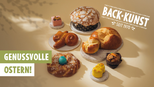 Eine Auswahl an Ostergebäck, darunter süßes Brot, eine Brezel und bunt dekorierte Leckereien, ausgestellt auf Marmorplatten. Der Text lautet "Backkunst seit 1970" und "Genussvolle Ostern!" auf hellem Hintergrund.