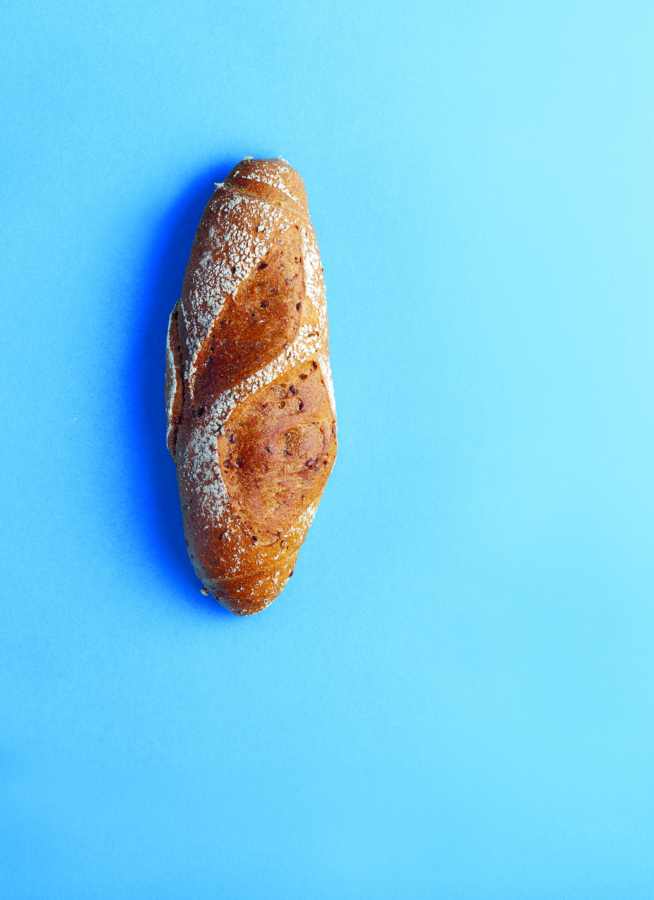 Ein einzelner rustikaler Brotlaib mit einer knusprigen, goldbraunen Außenseite befindet sich auf einem hellblauen Hintergrund.