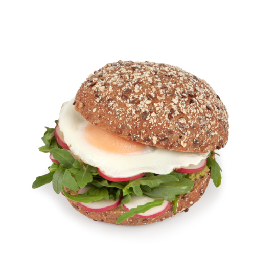 Ein Vollkornsandwichbrötchen, gefüllt mit grünem Rucola, Radieschenscheiben, Avocado und einem Spiegelei, vor weißem Hintergrund.