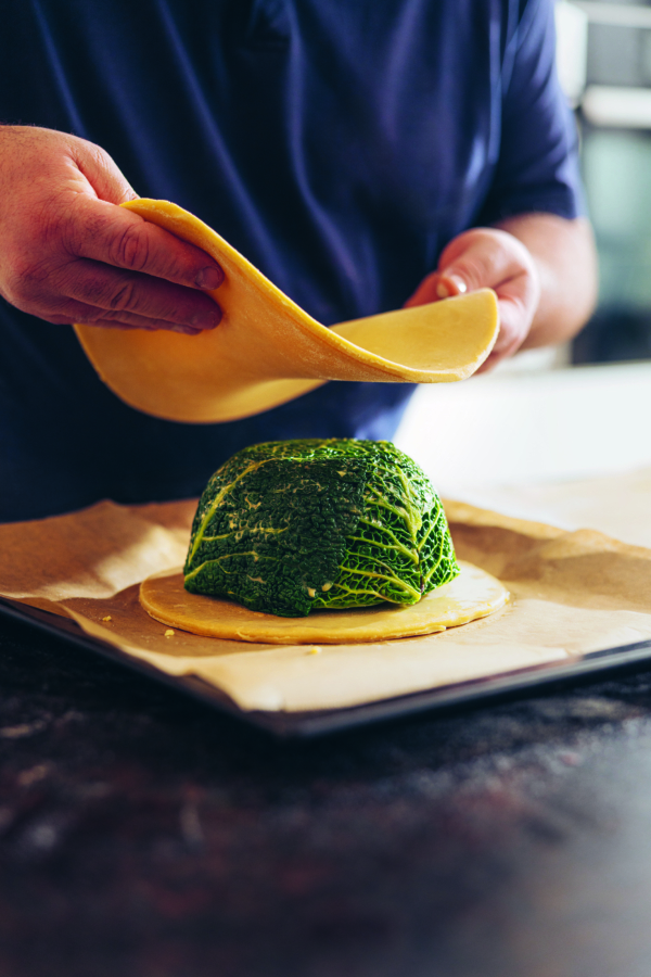 Auf ein mit Pergamentpapier ausgelegtes Backblech legt man eine Teigplatte über eine mit Wirsing umwickelte kuppelförmige Füllung.