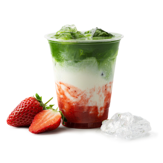 Ein durchsichtiger Becher, gefüllt mit einem geschichteten Getränk aus grünem Matcha, weißer Milch und rotem Erdbeerpüree, gekrönt mit Eis. Zwei frische Erdbeeren und Eiswürfel sind neben der Tasse auf weißem Hintergrund platziert.