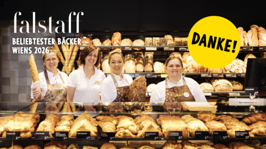 Vier Bäckereimitarbeiter lächeln hinter einer mit Brot und Gebäck gefüllten Vitrine, dazu der Text Falstaff BELIEBTESTER BÄCKER WIENS 2026 und ein gelber Kreis mit der Aufschrift DANKE!.