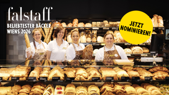 Vier Bäckereimitarbeiter stehen hinter einer Vitrine voller Brot und Gebäck, unter der die Aufschrift Falstaff BELIEBTESTER BÄCKER WIENS 2026 zu lesen ist, sowie ein gelber Kreis mit der Aufschrift JETZT NOMINIEREN!.
